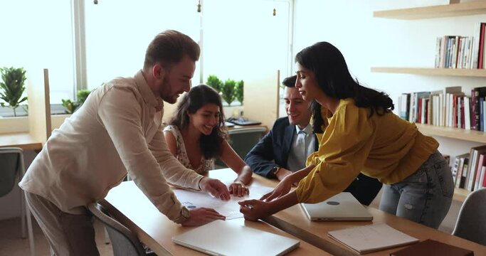 Diverse employees review report in charts and diagrams, learn infographic, analysing statistics, sales results, develop strategy, discuss deal benefits take part in group meeting in office boardroom