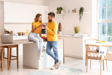 Happy couple in love drinking wine in kitchen - obrazy, fototapety, plakaty