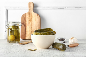 Obraz premium Bowl with tasty canned cucumbers on table near white wall