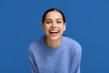 Beautiful young happy woman laughing on blue background