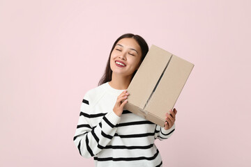 Pretty young woman with parcel on pink background