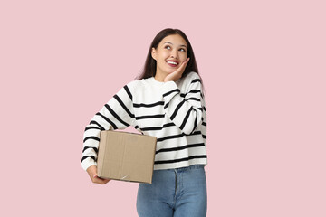 Pretty young woman with parcel on pink background