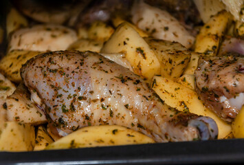 Raw chicken cut into pieces along with potatoes is baked in the oven. Baking chicken with vegetables. Seasoned Baked Potatoes.