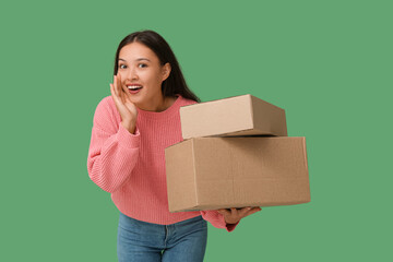 Happy young woman with parcels on green background