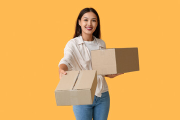 Pretty young woman with parcels on yellow background