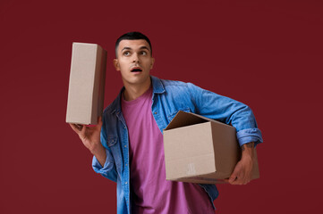 Curious young man holding parcels on red background