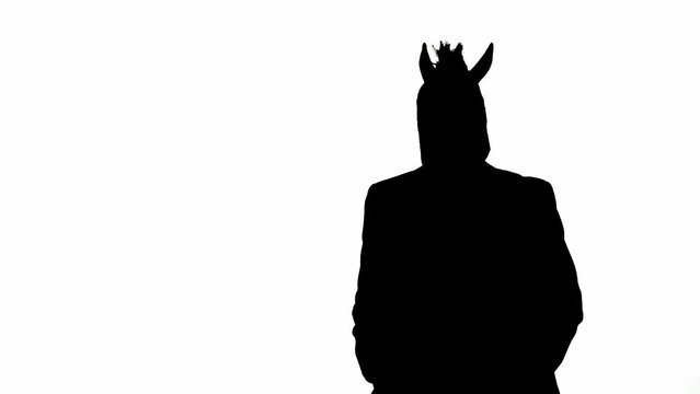 Black silhouette of man in business suit with horse head mask on white isolated studio background. Businessman walking. Concept of hard office work.