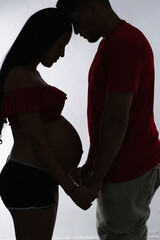 young Latino couple, holding hands as they join foreheads and pray for her pregnancy.