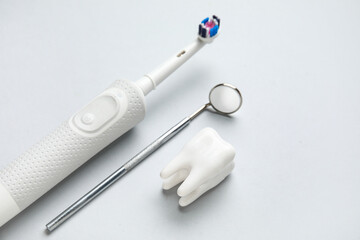 Dental mirror, tooth model and electric toothbrush on white background. World Dentist Day