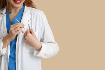 Female dentist with dental tools in pocket on beige background, closeup. World Dentist Day