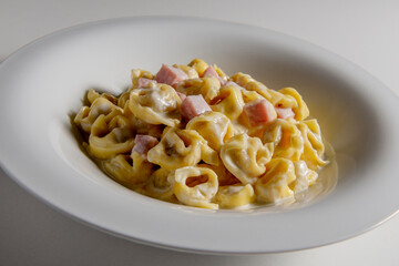 Soup bowl with tortellini pasta with cream and ham