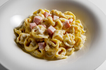 Soup bowl with tortellini pasta with cream and ham