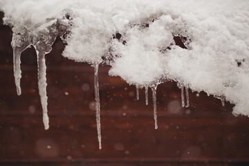 Icicles hang on the roof of a house. Winter landscape with icicles hanging from the roof of the...