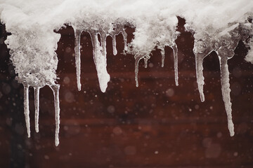 Icicles hang on the roof of a house. Winter landscape with icicles hanging from the roof of the...