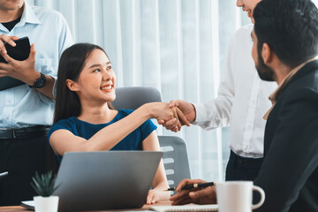 Diverse coworkers celebrate success with handshake and teamwork in corporate workplace. Multicultural team of happy professionals united in solidarity by handshaking in office. Concord