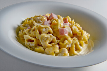Soup bowl with tortellini pasta with cream and ham