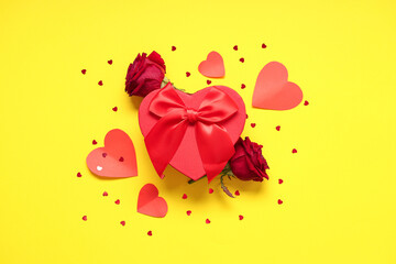 Composition with gift box, roses and paper hearts on yellow background. Valentine's day celebration