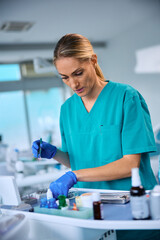 Female stomatologist choosing dental tools while working at dentist's office.