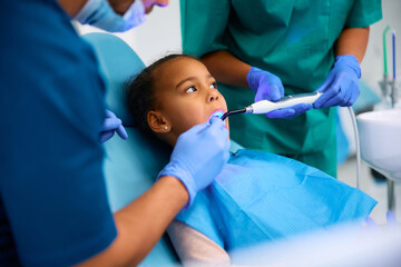 Black little girl during dental procedure at dentist's office.