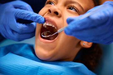 Close up of black little girl during teeth check-up at dentist's office.