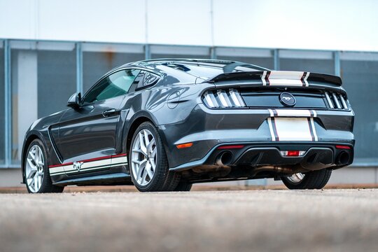 Gray Ford Mustang with glued white foil stripes, fast American sports car. Rear view of the car.