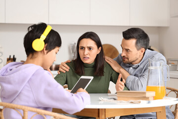 Upset parents with their teenage son at table in kitchen. Family problem concept