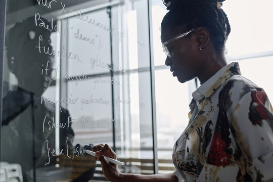 Young african american office employee writing code with white marker on glass board