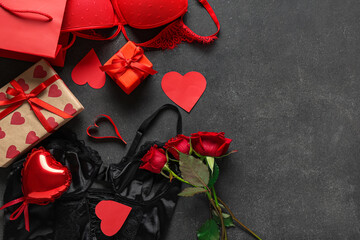 Shopping bag with sexy underwear, gift boxes and bouquet of roses on black background. Valentine's Day celebration