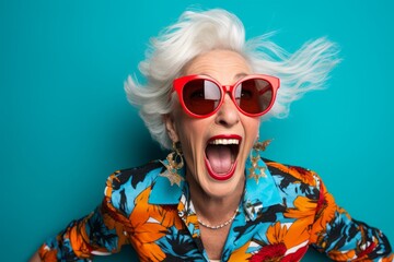 Funny old woman with sunglasses on a blue background. Studio shot.