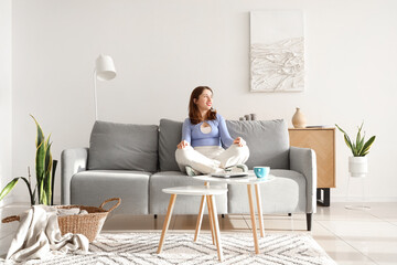 Young woman sitting on grey sofa at home