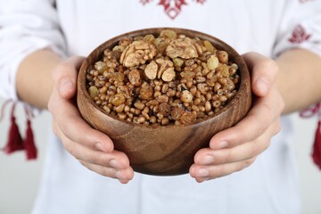 Woman in slavic shirt holding bowl with traditional kutia, closeup