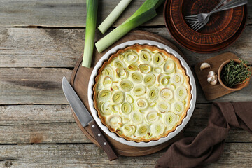 Tasty leek pie, knife and products on old wooden table, flat lay. Space for text
