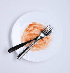 Dirty plate and cutlery on white background, top view