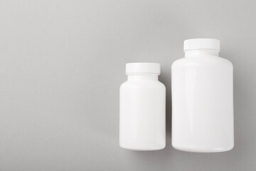Blank white pill bottles on light grey background, top view. Space for text