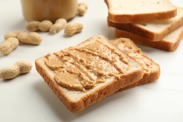 Delicious toasts with peanut butter and nuts on white table, closeup