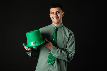 Happy young man with green hat on dark background. St. Patrick's Day