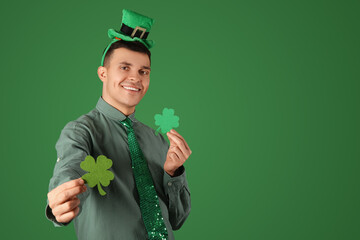 Happy young man with clovers on green background. St. Patrick's Day