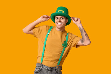 Happy young man in leprechaun's hat on yellow background. St. Patrick's Day