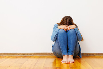 Distressed Woman Sitting on Floor Against Wall