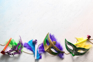Carnival masks with party horns and decor for Mardi Gras celebration on light blue background