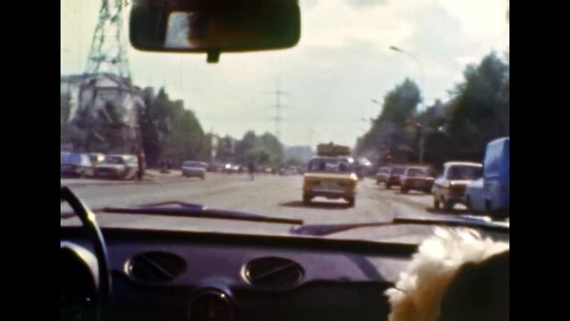 Road city streets view from moving car. Urban traffic view through windshield window of driving transport. Automobile in motion. Urban drive by highway. Vintage color film. Retro archive. Travel 1980s