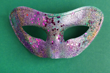 Shiny purple carnival mask for Mardi Gras celebration on green background