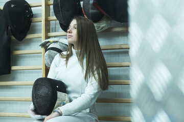 Professional fencer girl with fencing mask and rapier. Training in hall
