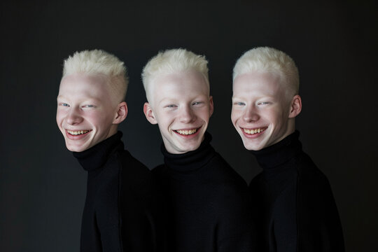 Three albino brothers. Triplets on black background in black turtlenecks