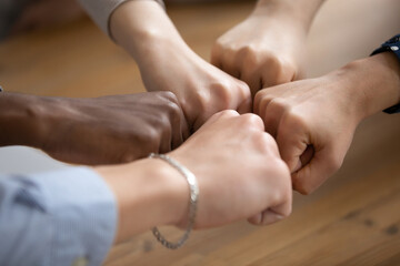 Close up of multiracial young people join clenched fists together show unity, support and teamwork...