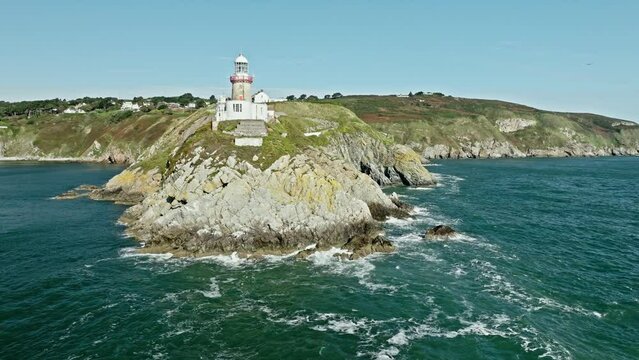 Lighthouse of Howth and waves crashing on the cliffs in Ireland, aerial view