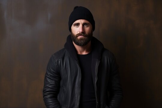Portrait of a handsome bearded man in a black leather jacket and hat