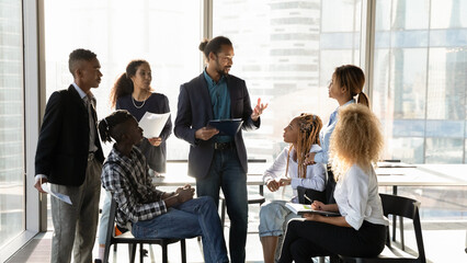 Business coaching. Young black male experienced mentor speak to mixed race group of students interns at seminar workshop. Interested millennial staff engaged in practical training on sales management