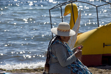 Bolivian woman eating jelly on the shore of Lake Titicaca