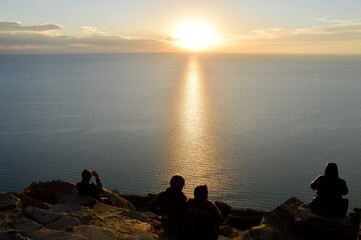 Unrecognizable tourists watching the sunset at Lake Titicaca